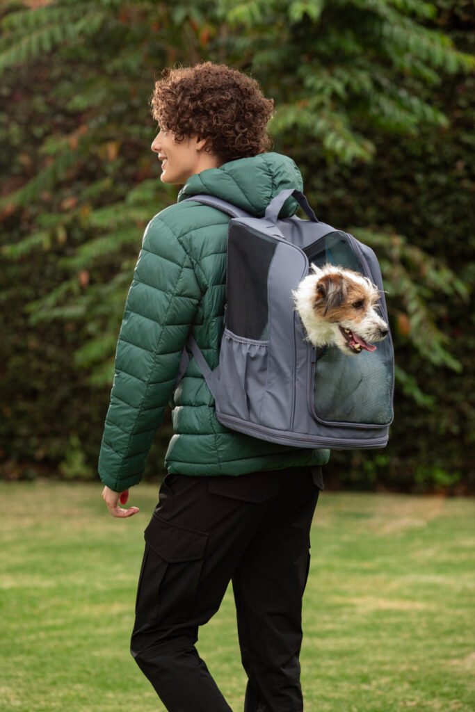 Hombre cargando perro en cargador para mascota - Viajar con mascotas